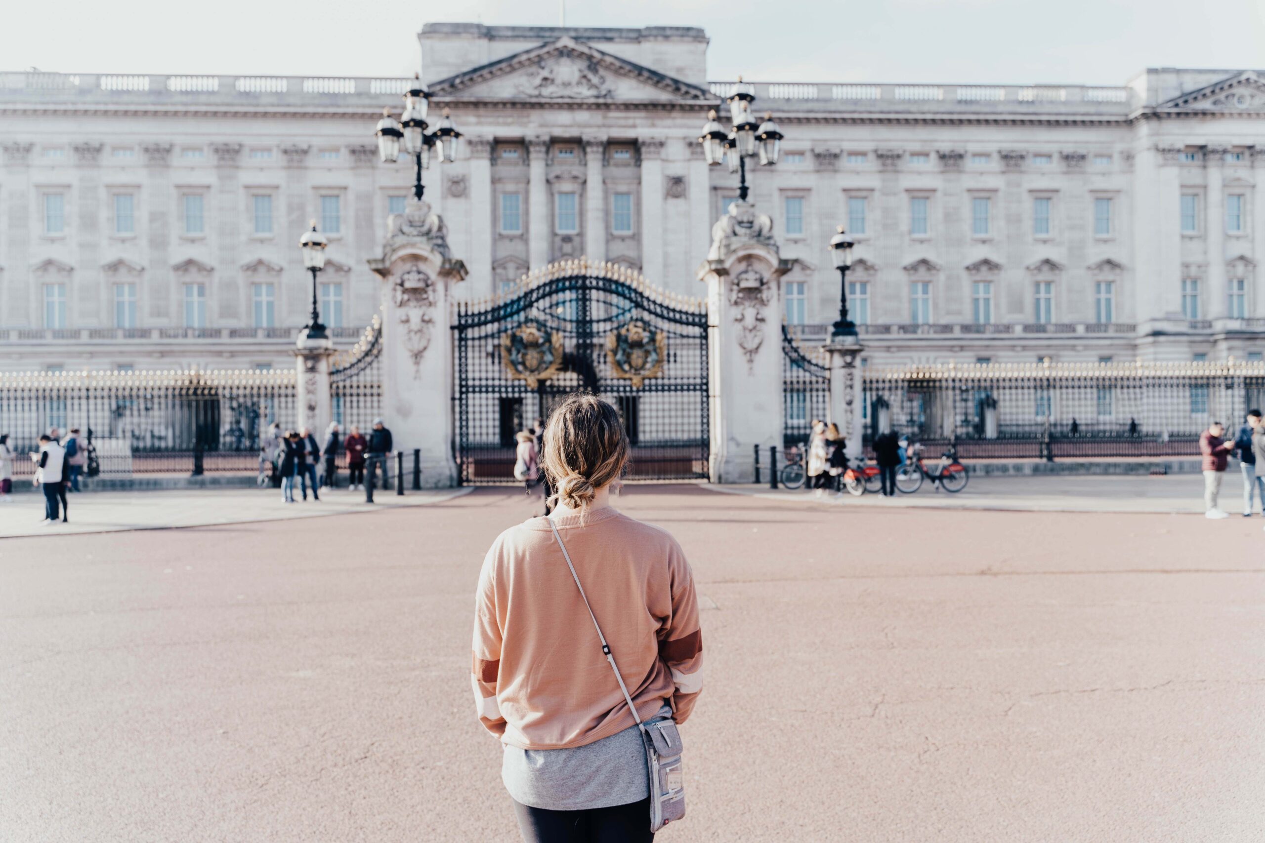 A solo traveler standing in front of the Buckingham Palace, one of the three official residences of the head of the british royal family