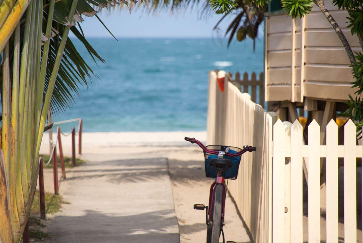 a bike, which is a popular green transportation option, rests on a fence in front of a beach in Miami