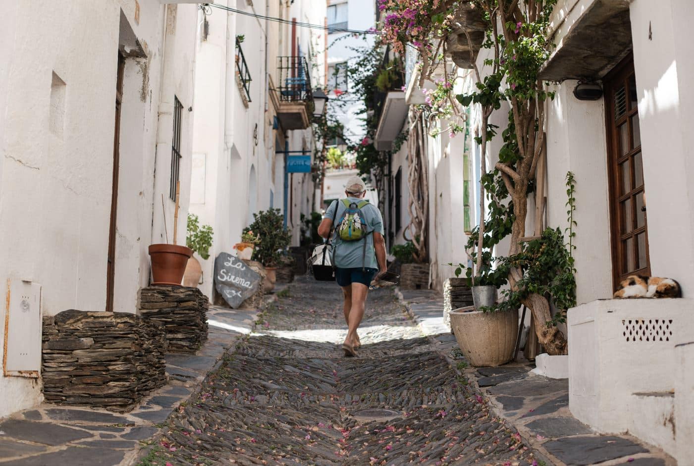 a visitor climbing up the narrow alley of Cadaques, a popular Barcelona day trip destination