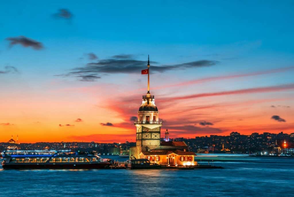 The Maiden's Tower lit up in preparation for nightfall, with a cruising Istanbul ferry passing by.