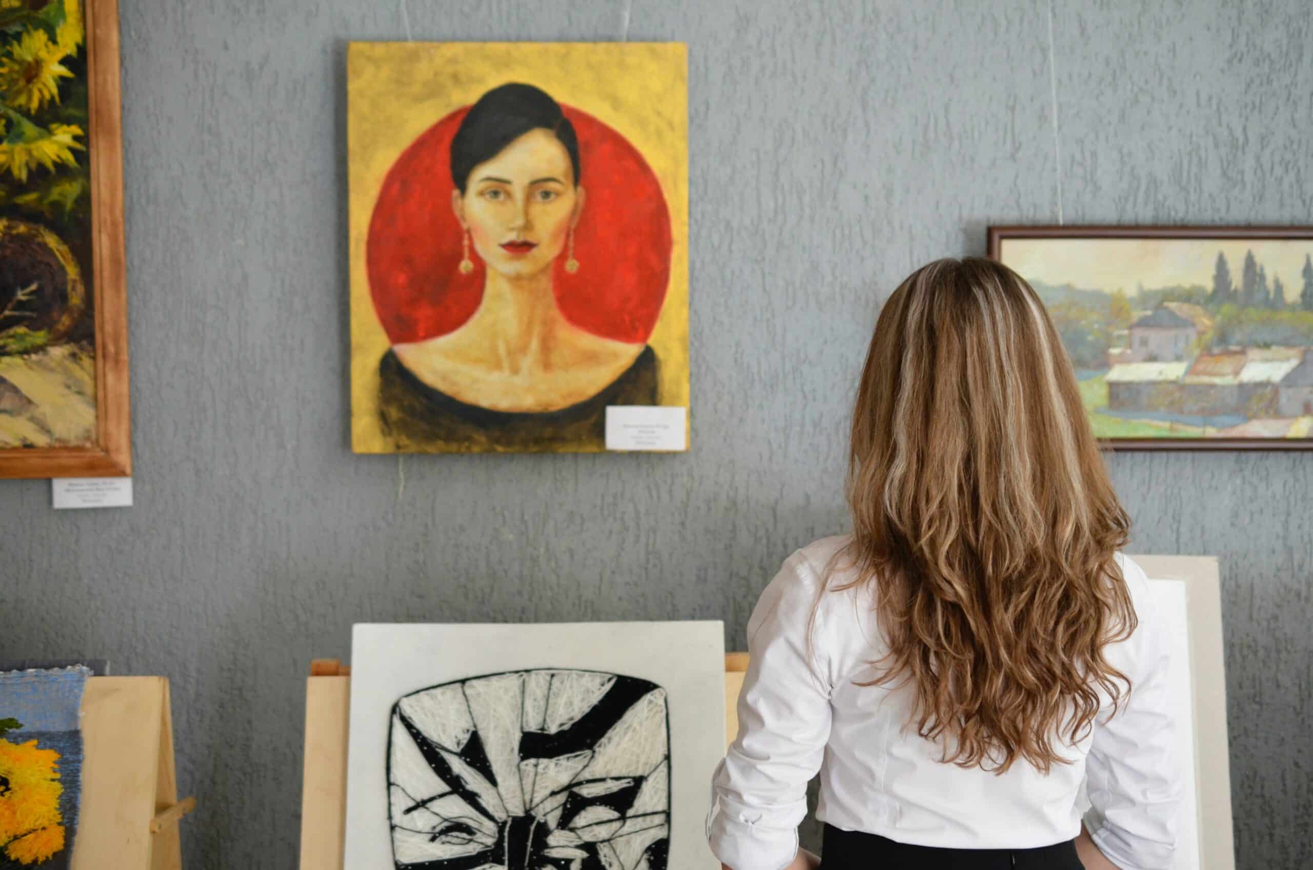 A woman looking at a painting inside an art gallery